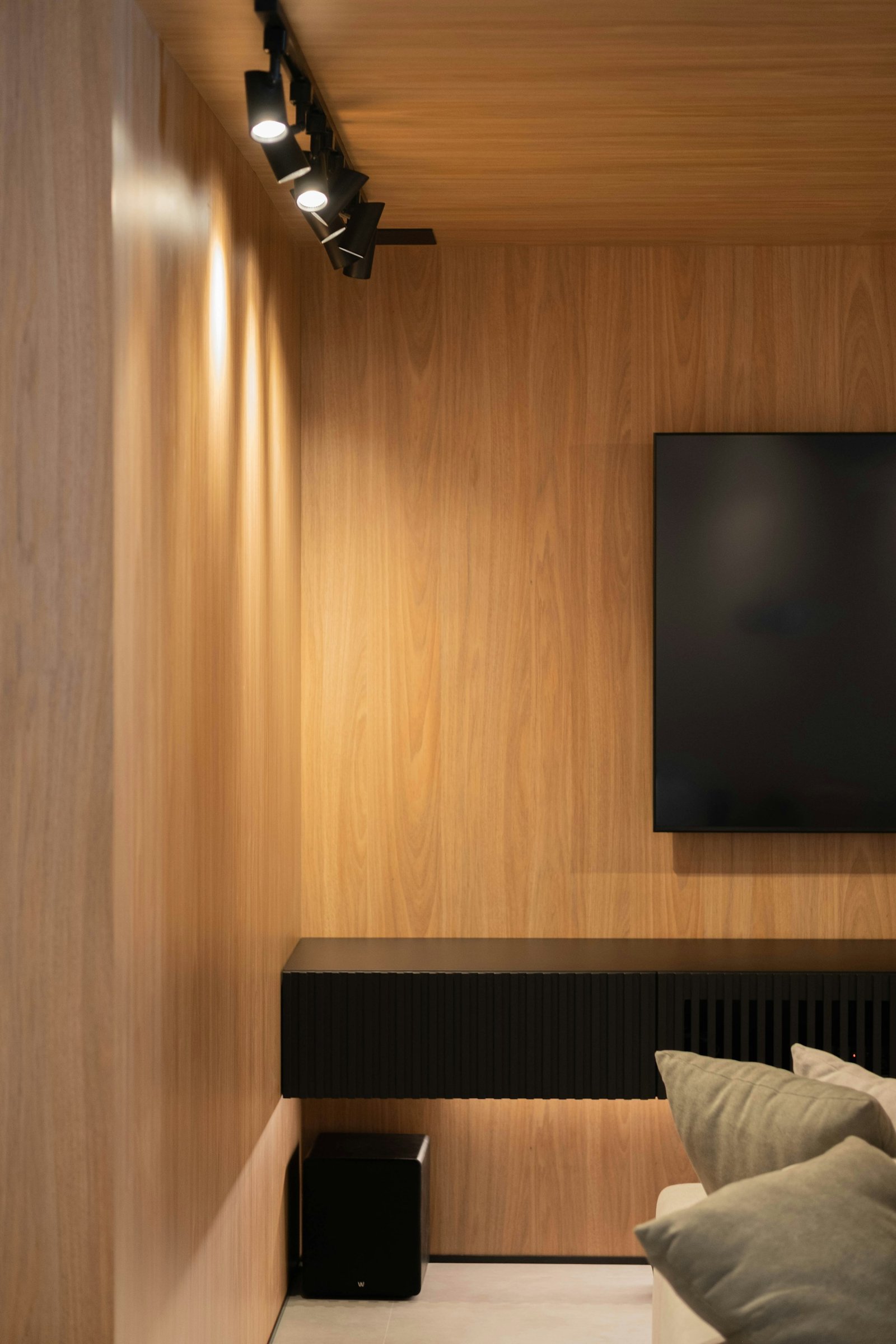 Living com painel contínuo de madeira e iluminação direcionada